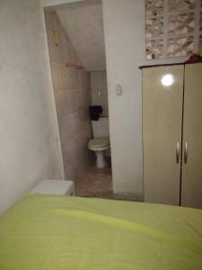 a bathroom with a toilet and a green bed at Casa da Vovó in Praia Grande