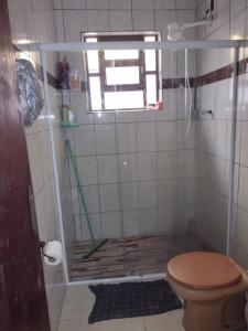 a bathroom with a shower with a toilet and a window at Casa da Vovó in Praia Grande
