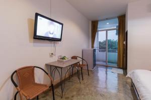 a room with a table and chairs and a tv on the wall at Tonwai Modern Place in Phitsanulok