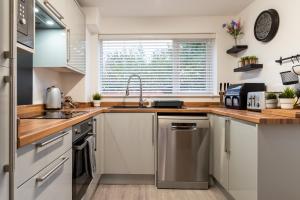 a kitchen with white cabinets and a sink at Triumph House in Hinckley