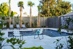 a patio with chairs and a pool with palm trees at Hotel Klaus in Opelousas