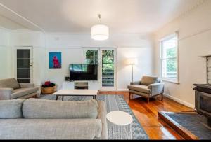 a living room with a couch and a tv at Warburton Bushland Retreat in Warburton