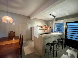 a kitchen with a bar with chairs and a table at TuriHouse - Ilha Grande in Abraão