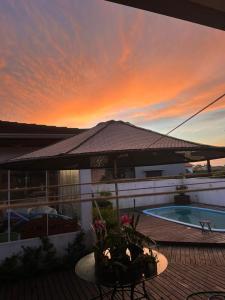 a sunset over a house with a patio with a pool at Casa de pedra in Arroio do Silva