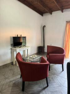 a living room with two chairs and a table and a tv at hospedaje la familia in Villa Lía +16 photos