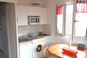 a kitchen with a table and a washing machine at Appartement à 20 m de la plage in Lacanau