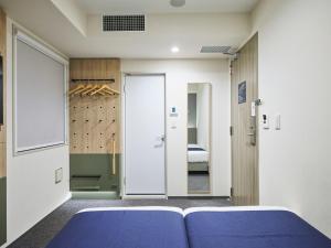 een slaapkamer met een blauw bed in een kamer bij hotel MONday Akihabara Asakusabashi in Tokyo