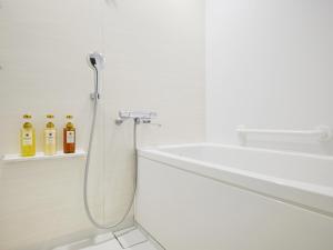 een witte badkamer met douche en wastafel bij hotel MONday Akihabara Asakusabashi in Tokyo