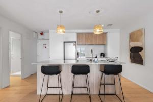 a kitchen with a counter and three bar stools at Oceanside Retreat Mt Maunganui in Mount Maunganui