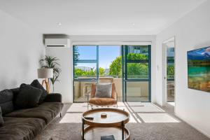 a living room with a couch and a table at Oceanside Retreat Mt Maunganui in Mount Maunganui