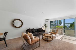 a living room with a couch and chairs and a table at Oceanside Retreat Mt Maunganui in Mount Maunganui
