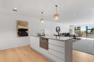 a kitchen with white cabinets and a living room at Oceanside Retreat Mt Maunganui in Mount Maunganui