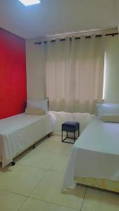 a bedroom with two beds and a red wall at Aparecida apartamento Rone 3 in Aparecida
