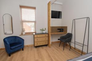a bedroom with a blue chair and a mirror at Amber Hotel in Hull