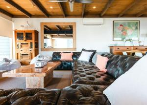 a living room with a leather couch and a table at Blue Pearl Retreat - Opp Beach, Spa, Sunsets and Pool in Mornington