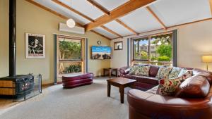 un salon avec un canapé et une télévision dans l'établissement Lavender Cottage By Wine Coast Holidays, à Aldinga Beach