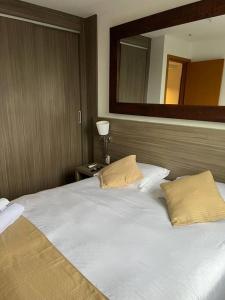 een slaapkamer met een groot wit bed met een spiegel bij Flat completo próximo ao Rio centro e Arena Carioca in Rio de Janeiro +7 foto's