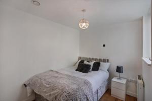 Dormitorio blanco con cama con almohadas negras en 2-Bed Apartment Sleeps 4 Free Parking, en Croydon