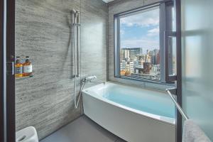 a bathroom with a bath tub and a window at FAV LUX Kagoshima Tenmonkan in Kagoshima +66 photos