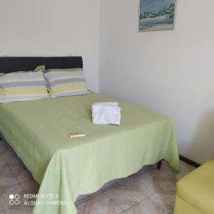 un letto con coperta verde e asciugamani di Apartamento na Graça a Salvador