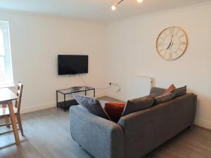 a living room with a couch and a clock on the wall at Large 2 beds flat- 3min walk from centre in Reading