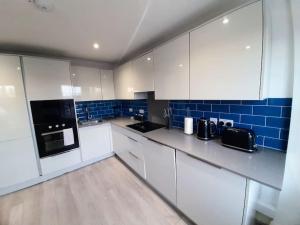 a large kitchen with white cabinets and blue tiles at Large 2 beds flat- 3min walk from centre in Reading