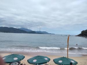 two green umbrellas on a beach with the ocean at Hospedagem casa da Lu in Paraty