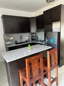 a kitchen with black cabinets and a counter with two chairs at Apartamentos victoria in Las Terrenas