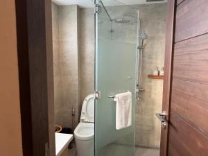 a bathroom with a toilet and a glass shower at Caracoa Resort in General Luna