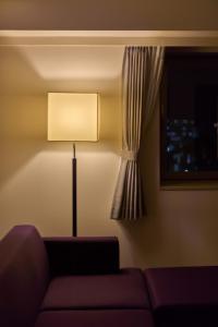 a living room with a couch and a lamp at Hotel Kanazawa in Kanazawa