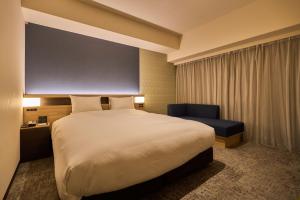 a hotel room with a large bed and a chair at Hotel Kanazawa in Kanazawa
