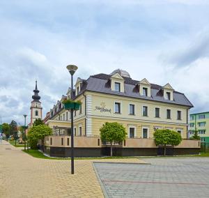 duży biały budynek z wieżą zegarową na ulicy w obiekcie Hotel Stefanik w mieście Myjava