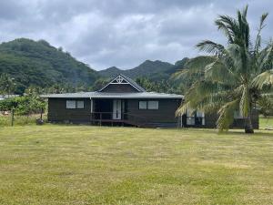 een huis met een palmboom in een veld bij Are Rera's Holiday Homestead in Rarotonga