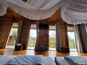 une chambre avec un lit avec des rideaux et des fenêtres dans l'établissement B'lao Corner Homestay, à Bảo Lộc