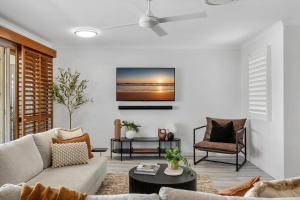una sala de estar con un sofá y una mesa en 3-Bed Haven with Balcony and BBQ, 5-Min to Beach, en Coolum Beach