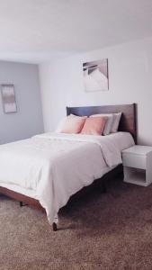 a white bedroom with a large bed with pink pillows at Home away from Home in Waldorf