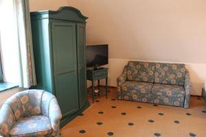 ein Wohnzimmer mit einem Sofa und einem Stuhl in der Unterkunft Müritz Landhotel Grüner Baum in Gotthun