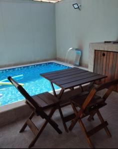 una mesa de picnic y 2 sillas junto a una piscina en Bela Mar Mongaguá, en Mongaguá