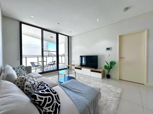 a living room with a couch and a television at Cosy 2-Bedroom Apartment, Homebush NSW 2140 in Sydney