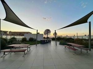 a group of picnic tables and benches on a patio at Cosy 2-Bedroom Apartment, Homebush NSW 2140 in Sydney