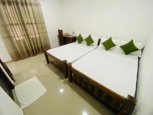 - une chambre avec 2 lits dotés d'oreillers verts et blancs dans l'établissement Premium Cottages B&B, à Kurunegala
