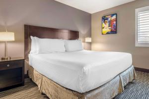 a large bed with white sheets and pillows in a room at Best Western McCarran Inn in Las Vegas