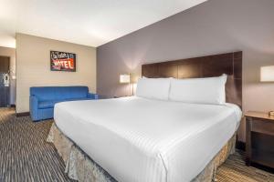 a hotel room with a large bed and a blue chair at Best Western McCarran Inn in Las Vegas