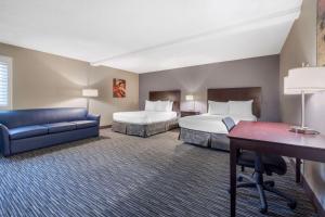 a hotel room with two beds and a blue couch at Best Western McCarran Inn in Las Vegas