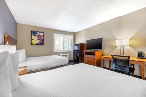 a hotel room with two beds and a desk with a computer at Best Western McCarran Inn in Las Vegas