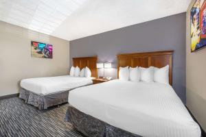 two beds in a hotel room with white sheets at Best Western McCarran Inn in Las Vegas