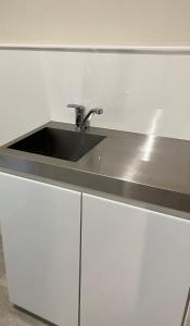 a kitchen counter with a sink and white cabinets at Restmance Pension Woody Hill in Iiyama