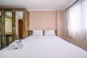 a bedroom with a large white bed and a window at Comfy and New Furnished at 2BR Kebagusan City Apartment By Travelio in Jakarta +20 photos