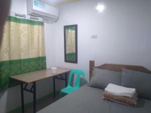 a bedroom with a table and a bed and a desk at Thomasita's Homestay in General Luna