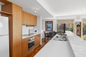 a kitchen with a white counter and a dining room at Apartment 5 Pacific Apartments in Lorne +7 photos